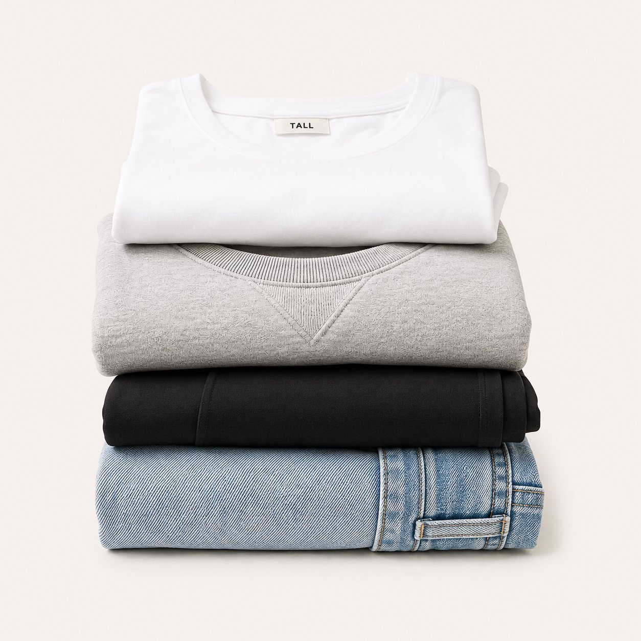 Folded tall women's essentials — white tee, grey crewneck, black leggings, denim